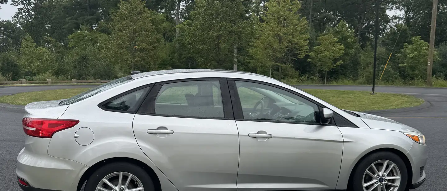 Silver Ford Focus sedan in side profile on a quiet road