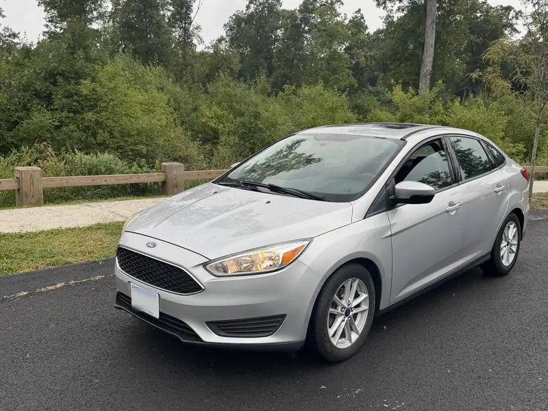 Silver Ford Focus sedan, front three-quarter view, parked on a curved road