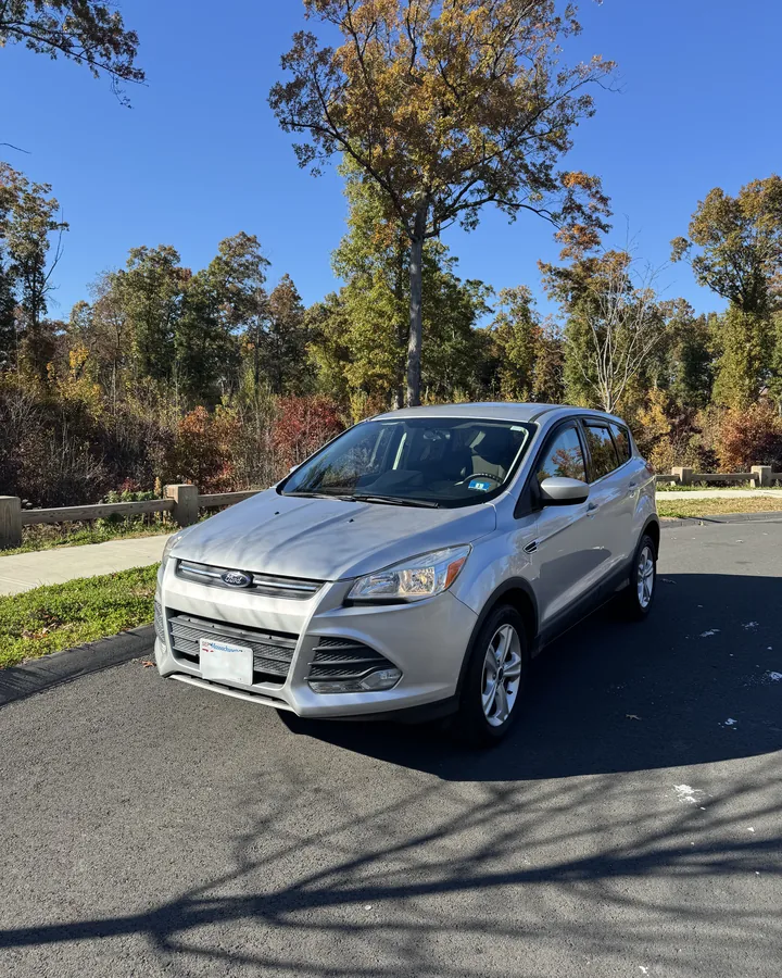 Silver Ford Escape SUV, front three-quarter view, parked by autumn trees