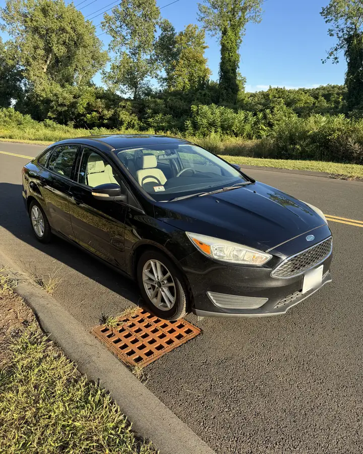 Black Ford Focus sedan at the roadside in evening light